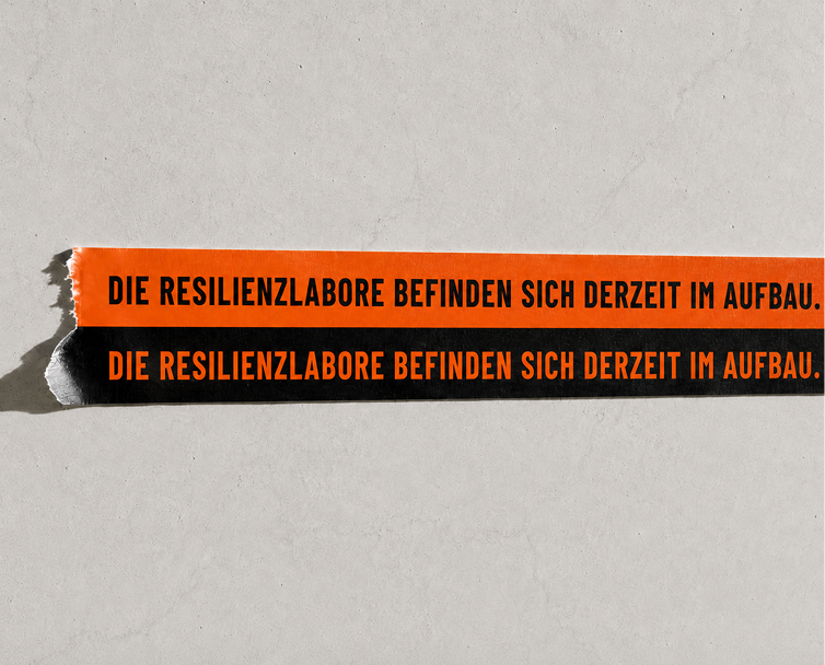 Zwei Streifen mit dem Text "DIE RESILIENZLABORE BEFINDEN SICH DERZEIT IM AUFBAU."